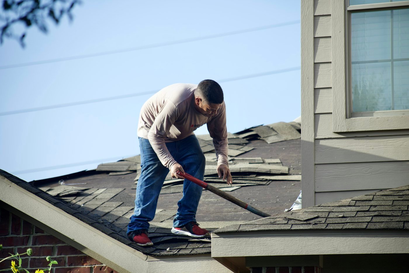 Tearing off old shingles from a roof